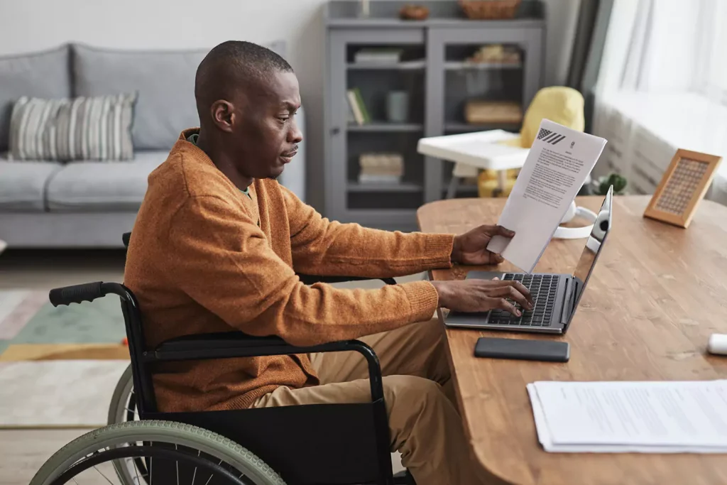 A physically disabled man is using his computer to make an enquiry
