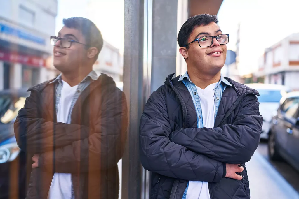 A young man with down syndrome is smiling while outdoors