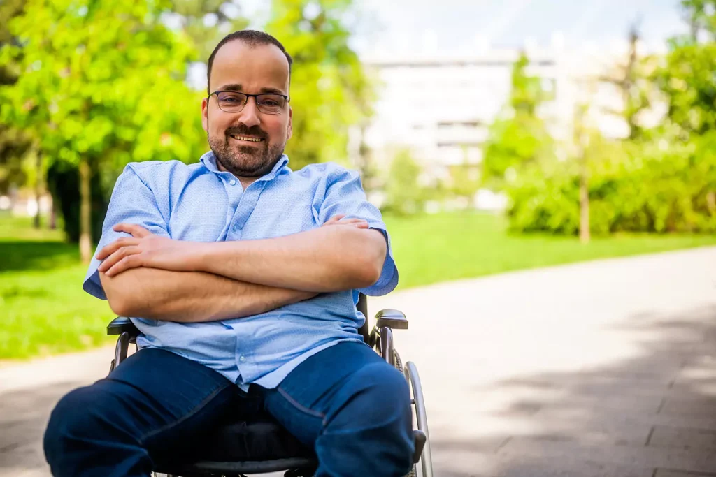 A physically disabled man is smiling while sitting at a local park